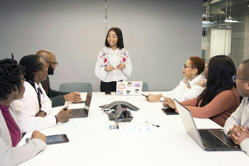 a group of people sitting around a table with laptops